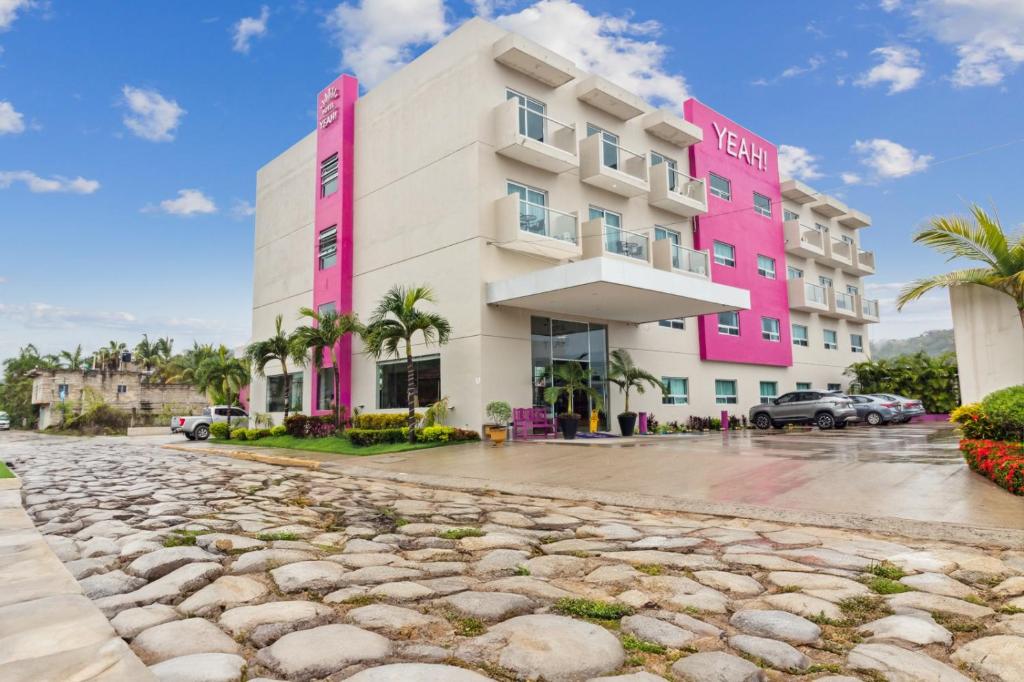 a pink and white building on a street at Hotel Yeah Rinc&oacute;n de Guayabitos in Rincon de Guayabitos