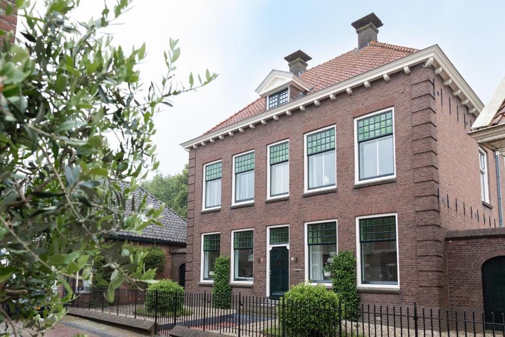 a brick house with a fence in front of it at Boutique Pastorale in Linschoten