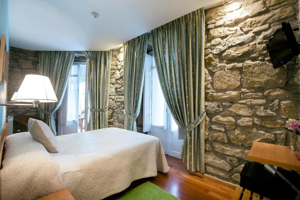 um quarto com uma cama e uma parede de pedra em Pensión Nuevas Artes em San Sebastián
