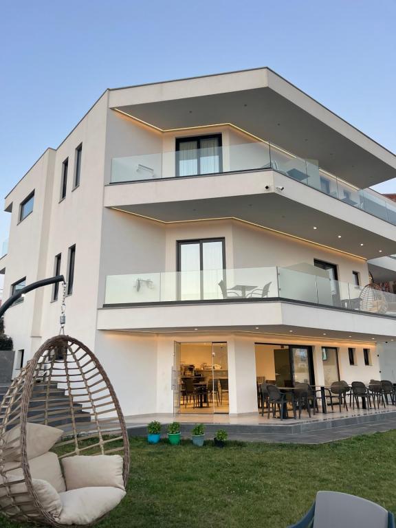a large white building with chairs and tables at Adele Hotel Ksamil in Ksamil