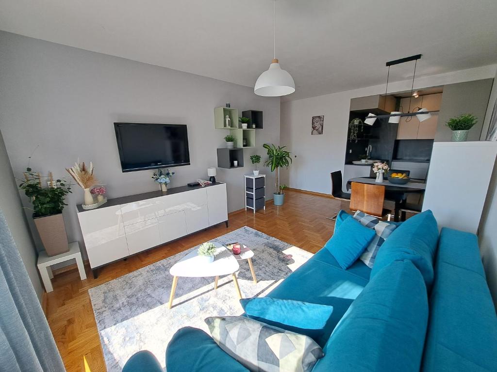 a living room with a blue couch and a tv at Apartment CityAna - private garage, 0-24 Self Check In in Zagreb