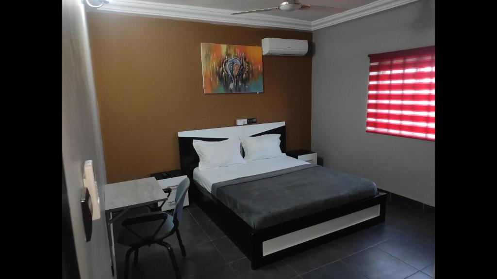 a small bedroom with a bed and a desk at Deluxe Double Bed in Royal Blue Guest House and Bar 02 in Lomé