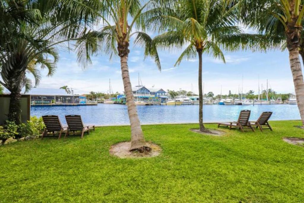 a group of chairs sitting next to a river with palm trees at Sailfish Suites - 11 - pet friendly in Stuart