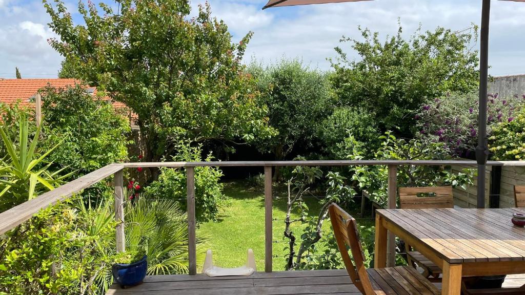 een terras met een tafel en stoelen en een tuin bij Le Bayanas in La Rochelle