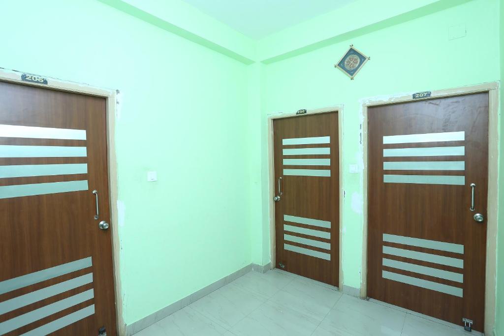 two wooden doors in a room with a wall at OYO Sambit Nx in Bhubaneshwar