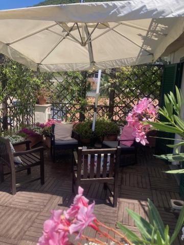 a patio with chairs and an umbrella and flowers at Hepburn Holiday Home in Salerno