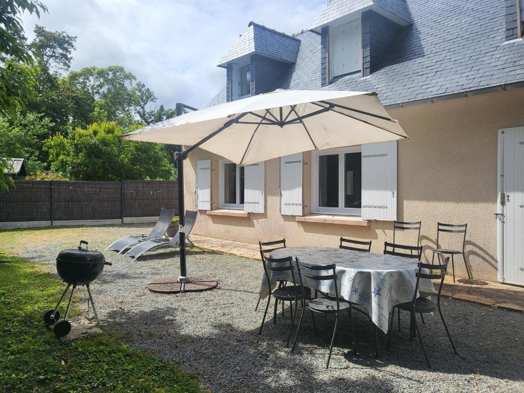 - une table avec un parasol, des chaises et un grill dans l'établissement L'échappée Belle à 5 minutes de la plage, à Fouesnant