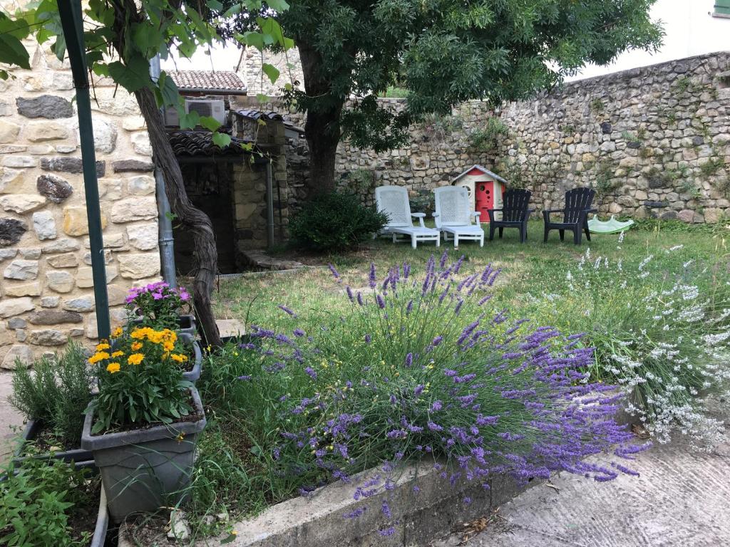 un jardin avec des fleurs et des chaises et un mur de pierre dans l'établissement chez Gaëlle et Martin, à Saint-Vincent-de-Barrès
