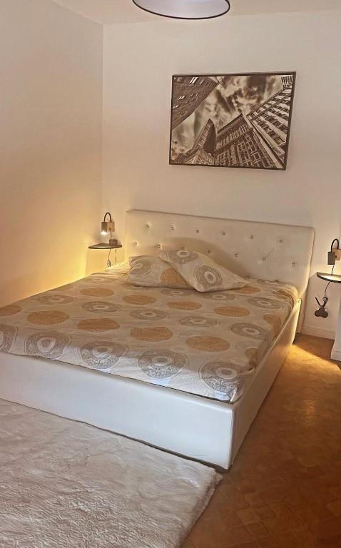 Ce lit se trouve dans une chambre avec deux lampes et une photo. dans l'établissement Appartement, à Montceau-les-Mines