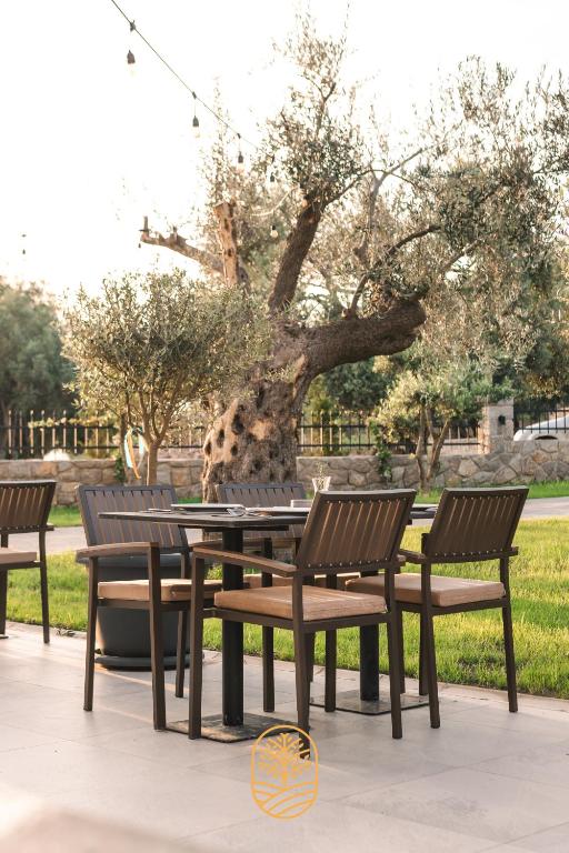 a picnic table and four chairs in front of a tree at CAROLEA VILLAS in Ulcinj