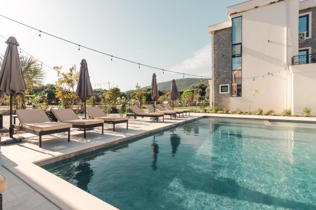 a pool with chairs and umbrellas next to a building at CAROLEA VILLAS in Ulcinj