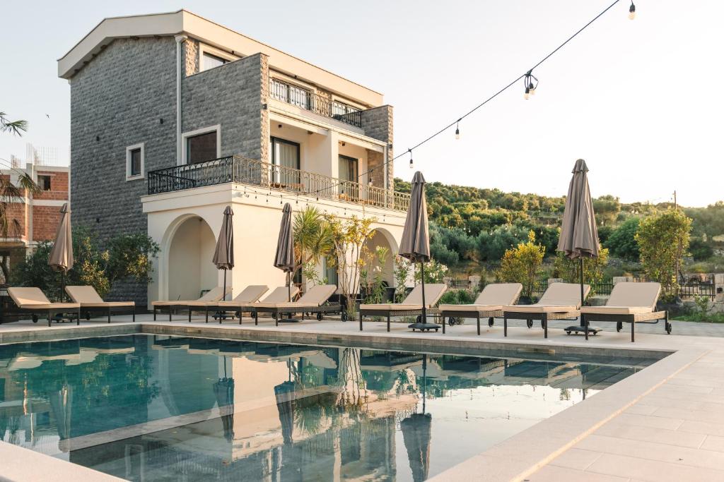 a pool with chairs and umbrellas next to a building at CAROLEA VILLAS in Ulcinj