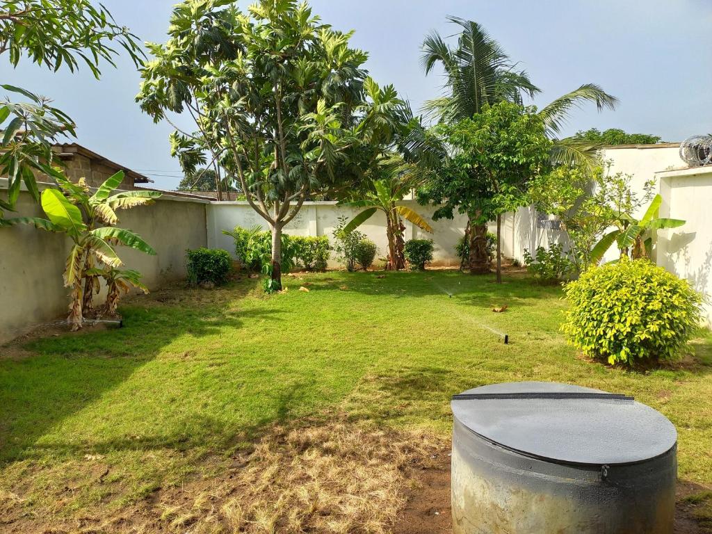 un cortile con un bidone dell'immondizia nell'erba di Villa Jardin d' Eden a Lomé