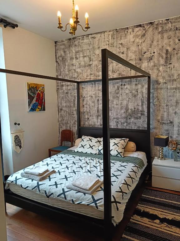 - une chambre avec un lit à baldaquin noir et un mur en briques dans l'établissement Les chambres des artistes, à Laguépie