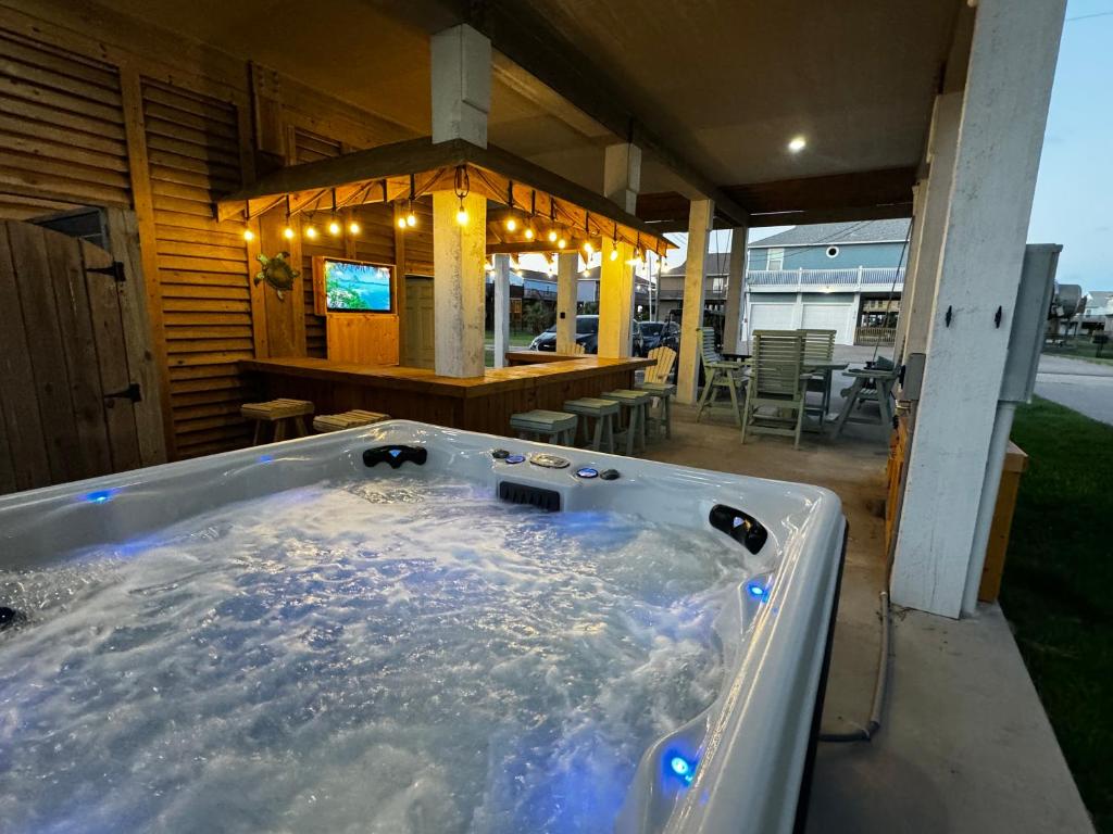 ein Whirlpool auf einer Terrasse mit einer Bar in der Unterkunft Hot Tub, Gas Grill, Tiki Bar w/TV, Dog Friendly in Bolivar Peninsula
