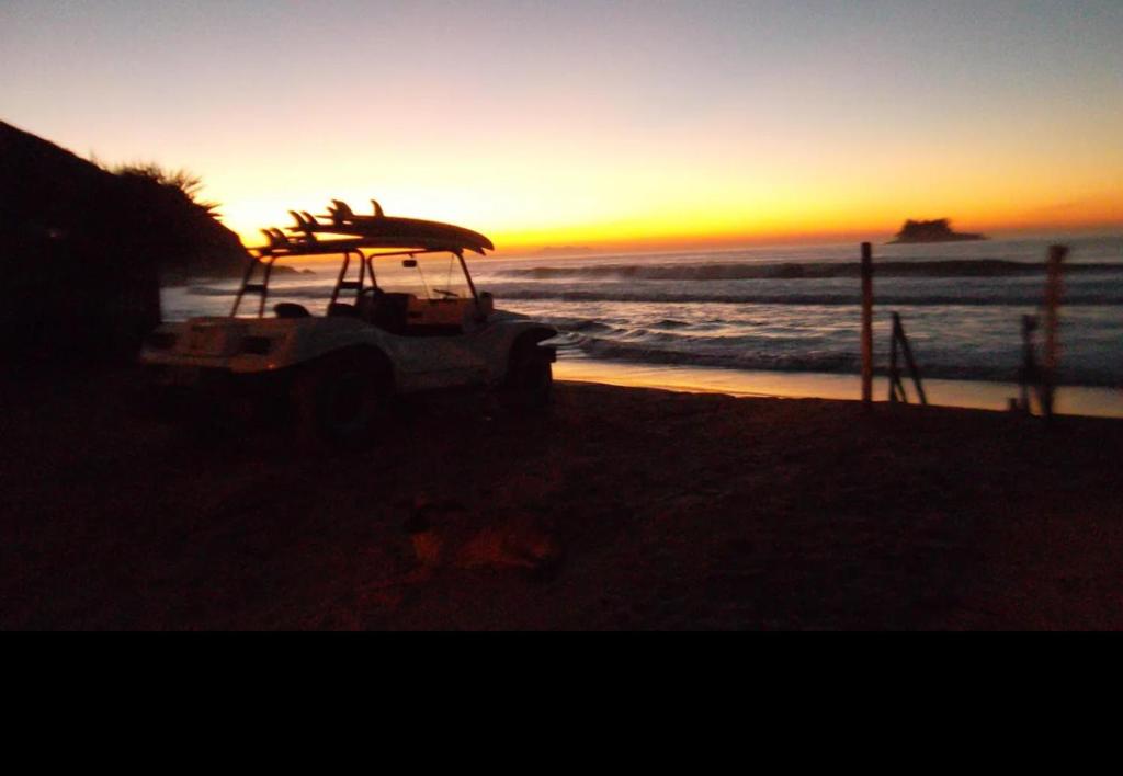 un coucher de soleil sur la plage avec une planche de surf sur un véhicule dans l'établissement Suíte Praia em Guarujá, à Guarujá