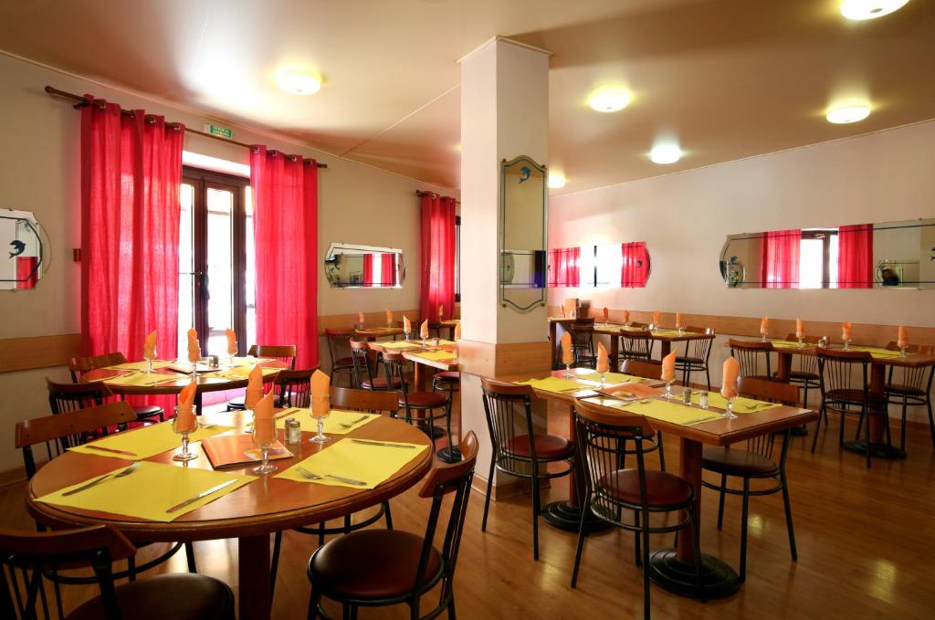 a restaurant with wooden tables and chairs and red curtains at Hotel le Dauphin in Ajaccio