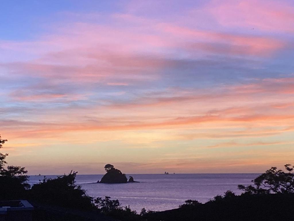 un tramonto sull'oceano con una roccia in acqua di Paseo Divino At Las Catalinas a Playa Danta