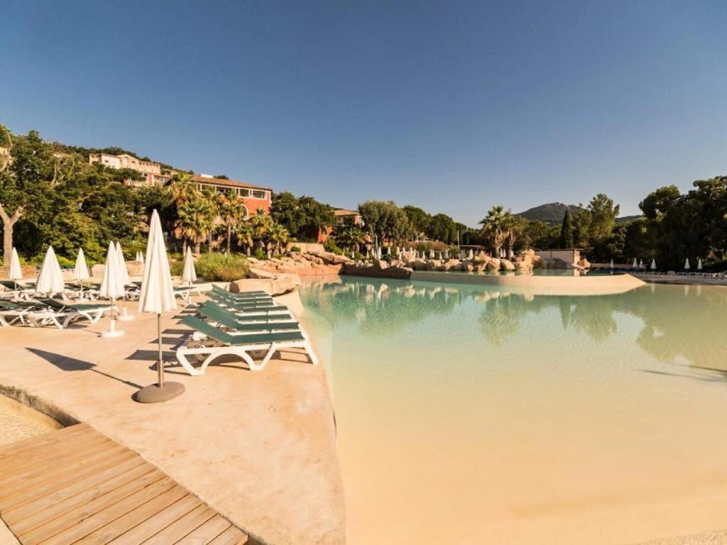une piscine avec chaises et parasols dans un complexe hôtelier dans l'établissement Les Appartements aux Restanques du Golfe de St Tropez - maeva Home - Appartement rooftop vue mer 3 Pièces 6 Personnes - Sélection MAE-3084, à Grimaud