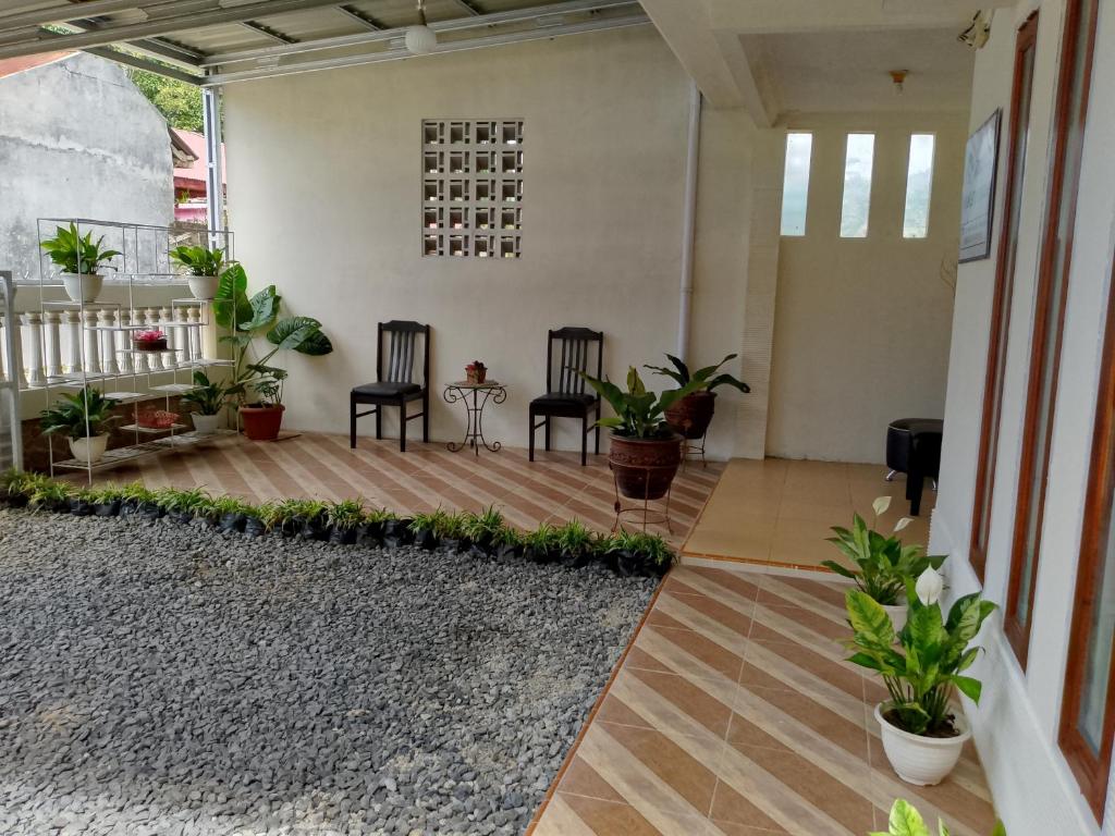 a living room with two chairs and plants at Firza Maqita Homestay Syariah in Payakumbuh