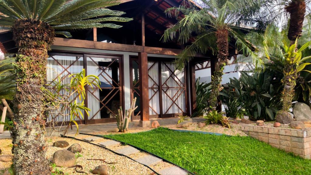 a house with palm trees in front of it at Pousada DRIRIOS HOUSE in Jaraguá do Sul