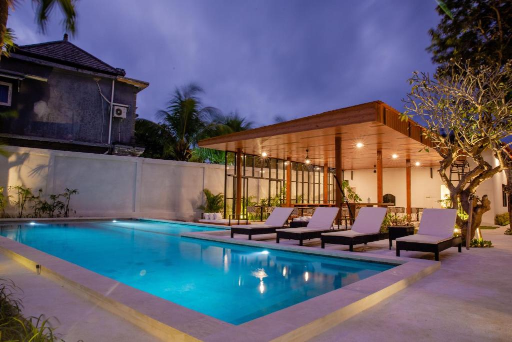 a swimming pool with lounge chairs next to a house at Ratan Uluwatu Hotel and Villas in Uluwatu