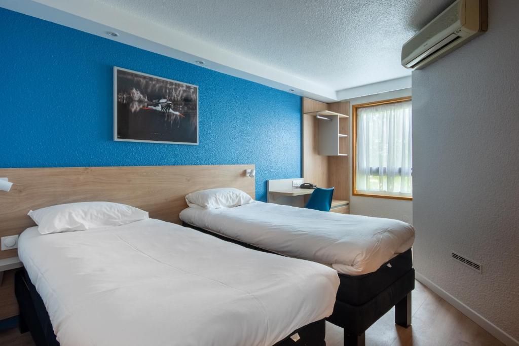 two beds in a hotel room with blue walls at Brit Hotel Mulhouse Centre in Mulhouse
