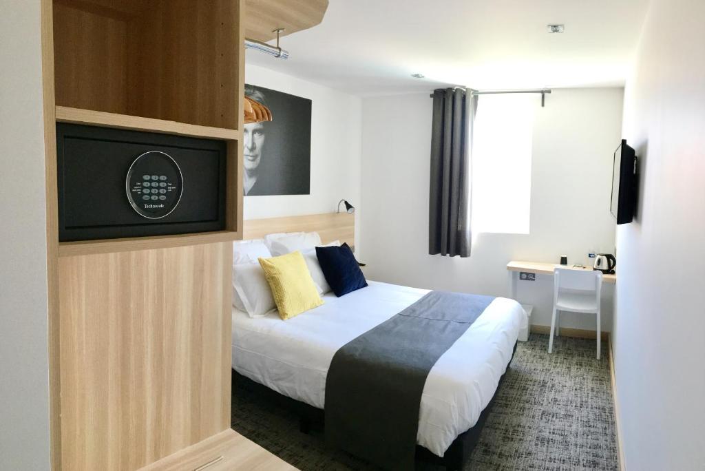 a hotel room with a bed and a flat screen tv at Brit Hotel Martigues Nord in Martigues