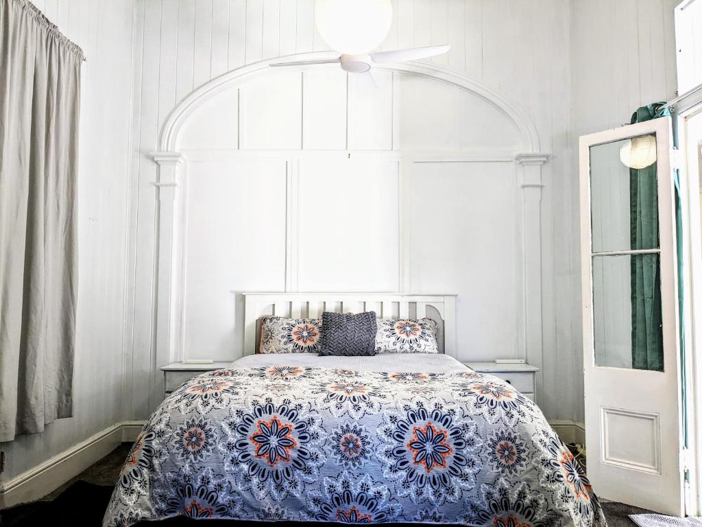 a bedroom with a blue and white bed with a ceiling fan at Classic Queenslander Suite in Townsville