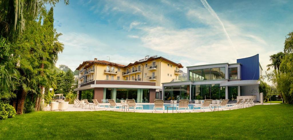 a large building with chairs in a yard at Villa Nicolli Romantic Spa Resort - Adults Only in Riva del Garda