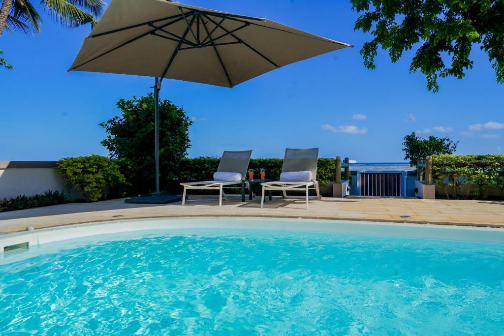 a patio with an umbrella and two chairs and a pool at The Compound - Villa 3 in Baie du Tombeau