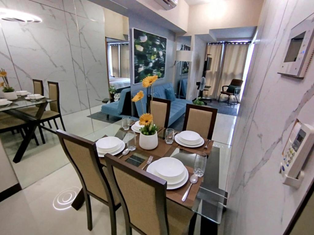 マニラにあるCozy 1BR UPTOWN PARKSUITES Tower1 BGCのテーブルと椅子のあるダイニングルームとリビングルーム
