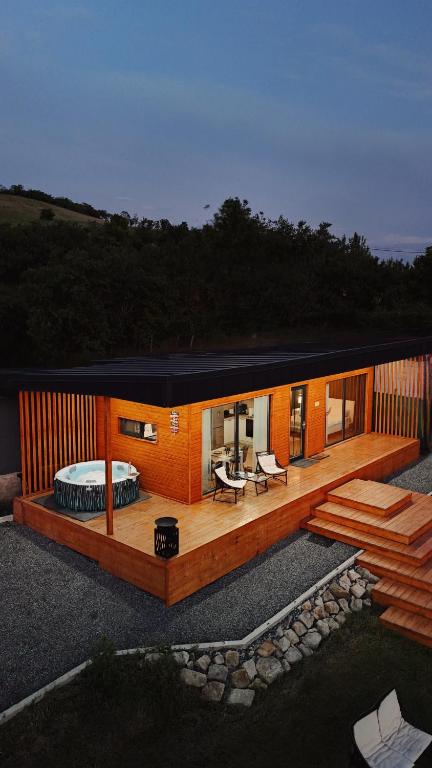 a house with a deck with a couch and a table at Story Cabin Lake in Cîmpeneşti