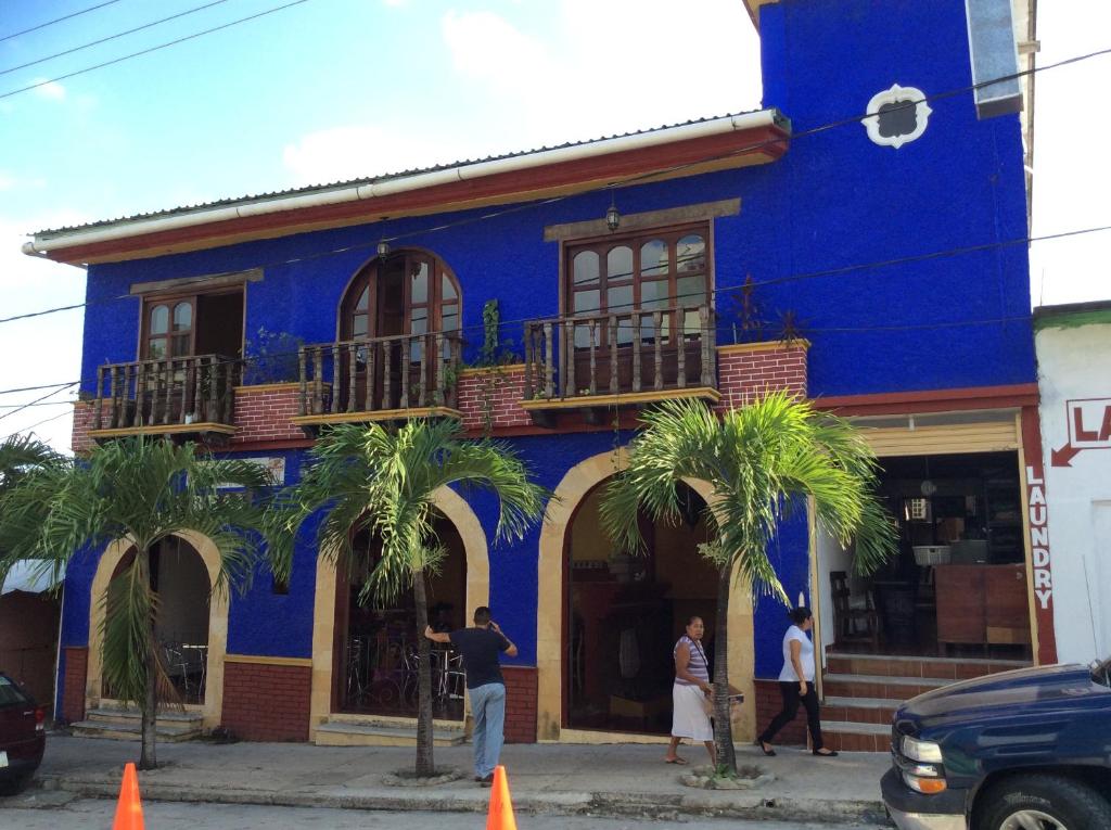 un bâtiment bleu avec des palmiers devant lui dans l'établissement Posada Aguila Real, à Palenque
