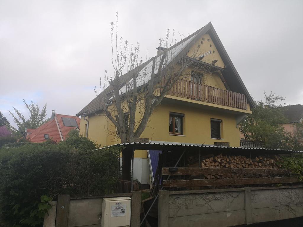 une maison jaune avec un balcon au-dessus dans l'établissement Beaux prés 68, à Colmar