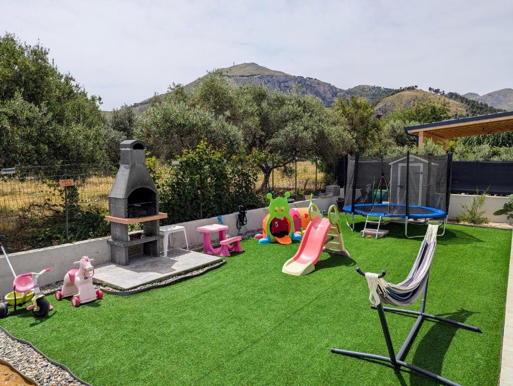 une cour arrière avec une pelouse avec des jouets et une aire de jeux dans l'établissement Villa Milicia, à Altavilla Milicia