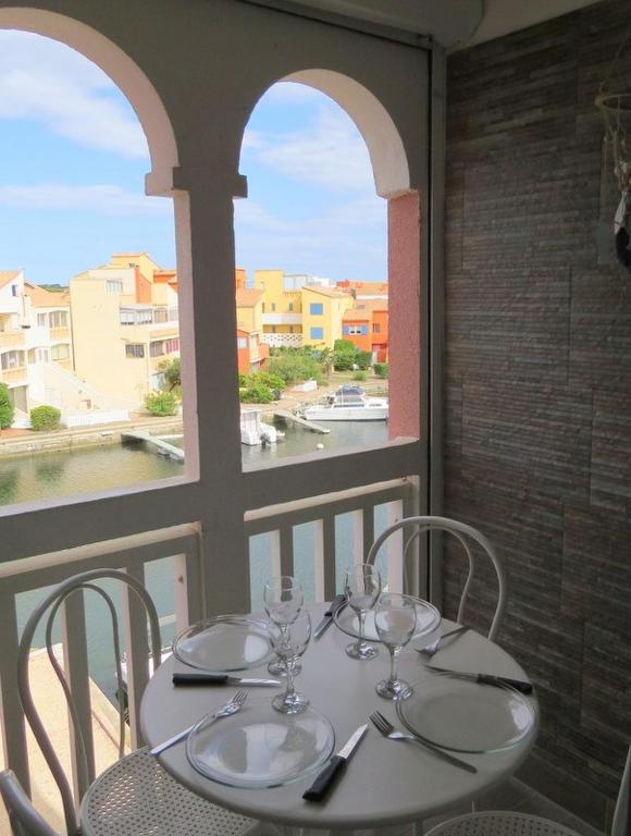 une table avec des chaises et des verres à vin sur un balcon dans l'établissement Superbe Studio Cabine Face Marina- résidence Piscine - 2 ou 3 personnes - 4PV47E, au Barcarès