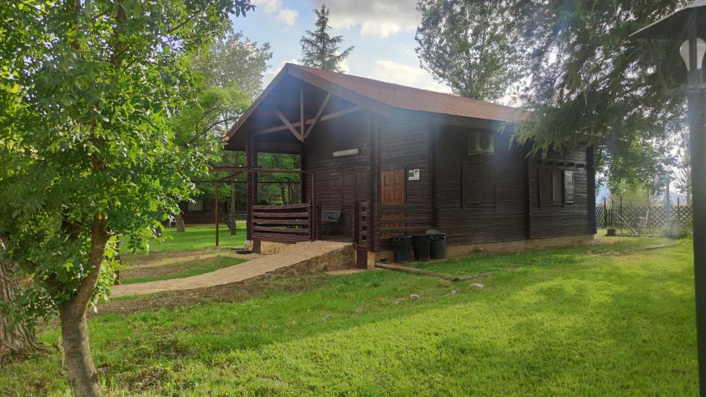 a small wooden cabin in a grassy field at Casas Rurales Tabla Honda in El Robledo