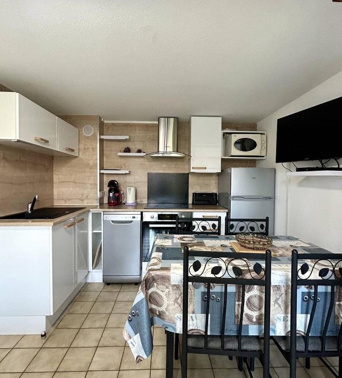 une cuisine avec des armoires blanches et une table avec des chaises dans l'établissement Très bel appartement pour 5 personnes 5PING121, à Port-Leucate