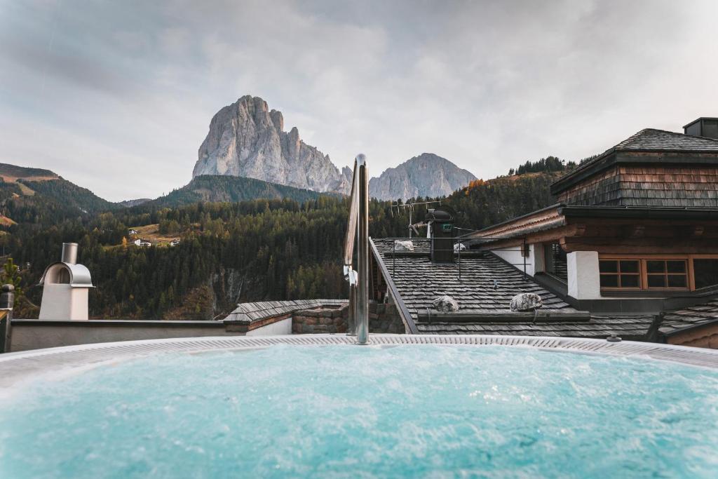 a hot tub with a view of a mountain at Dorfhotel Beludei in Santa Cristina in Val Gardena