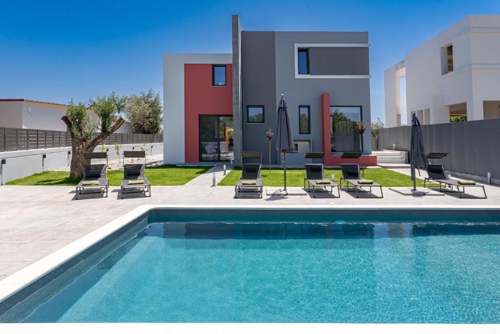 a swimming pool with chairs and a house at Villa Pasadra in Afantou