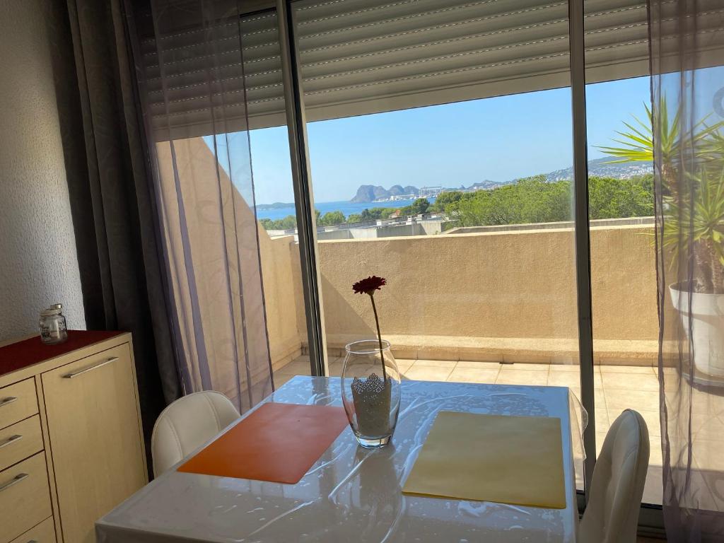 une table avec un vase et une fleur sur elle dans l'établissement Location t2 vue magnifique sur la baie de La Ciotat, à La Ciotat