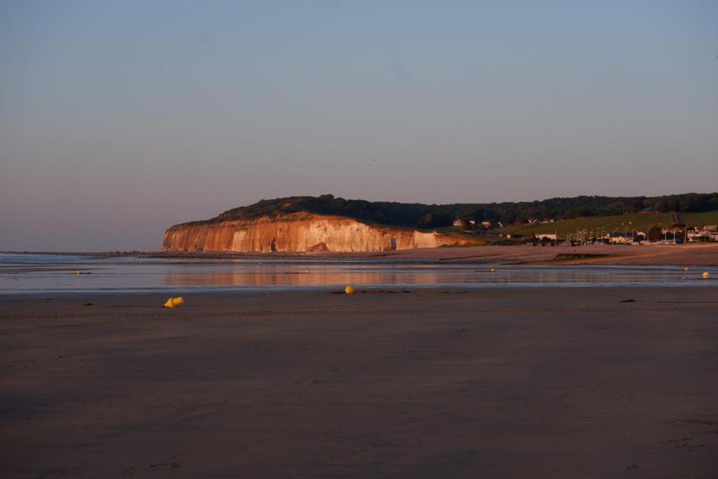 a sandy beach with a cliff in the background at maison familiale proche plage in Quiberville