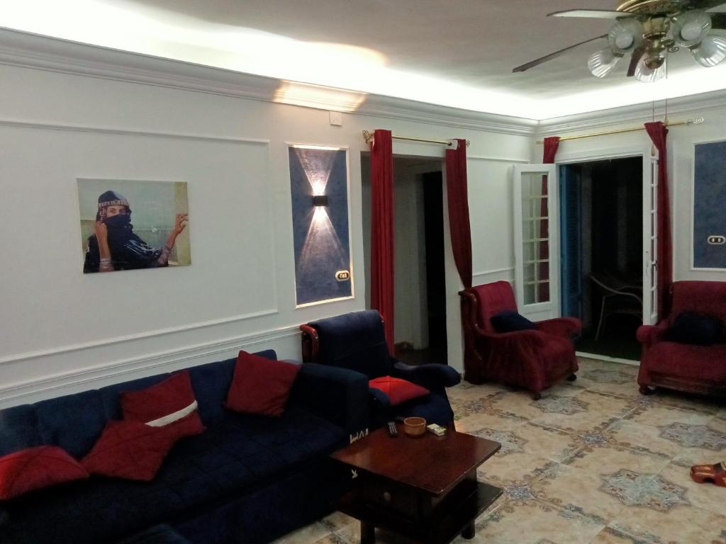 a living room with a blue couch and red chairs at شقه مصيفيه للايجار مباشره على البحر في مصطفى كامل الظباط in Alexandria