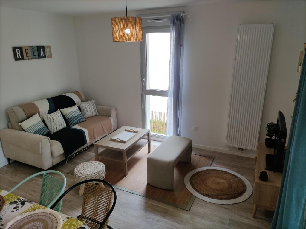 ein Wohnzimmer mit Sofa und Tisch in der Unterkunft La Nouvelle Vague in Carcans