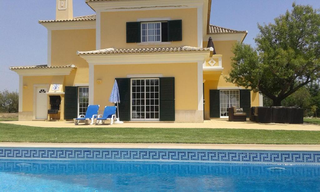 a villa with a swimming pool in front of a house at Casa dos Ventos in Olhão