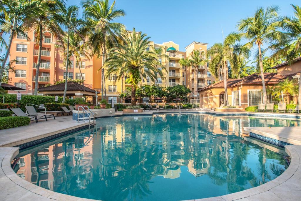 a pool at a resort with palm trees and buildings at Yacht Club Newly renovated parking included in Aventura