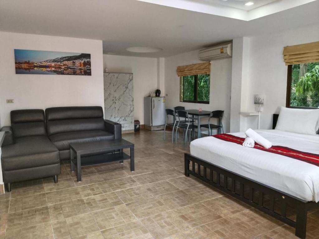 a bedroom with a bed and a couch and a table at Phratamnak Inn guesthouse - 100 mtr from the beach in Pattaya South