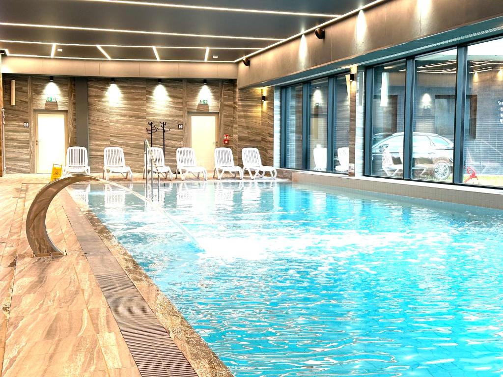a large swimming pool with white chairs in a building at Baltic Comfort SPA Apartment - FREE swimming pool, saunas & fitness - Kasprowicza 20 in Kołobrzeg
