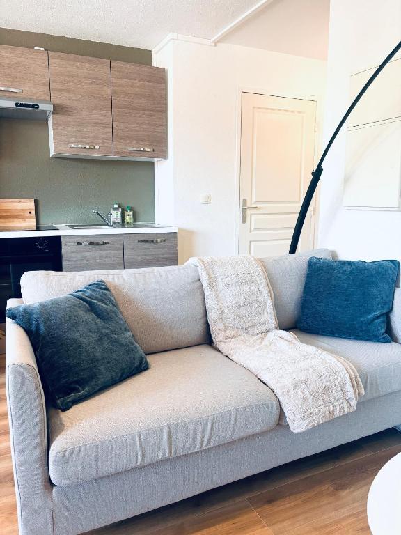 un canapé avec des coussins dessus dans un salon dans l'établissement Le Studio de Jeanne, à Mont-de-Marsan